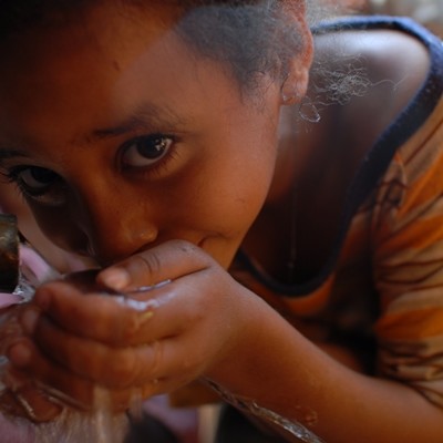 Child drinking from Fairtrade-funded protected spring, Haro, Ethiopia